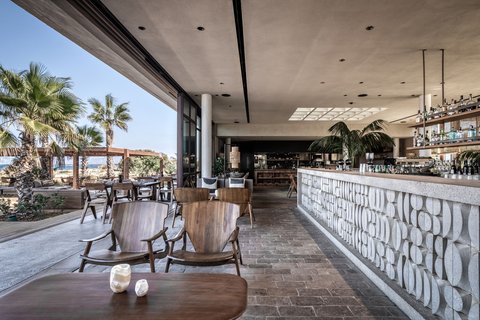 Domes Zeen Chania kūrorta atvērtā tipa bārs un atpūtas zona ar koka mēbelēm, skatu uz palmām un piekrasti Hanijā, Krētā