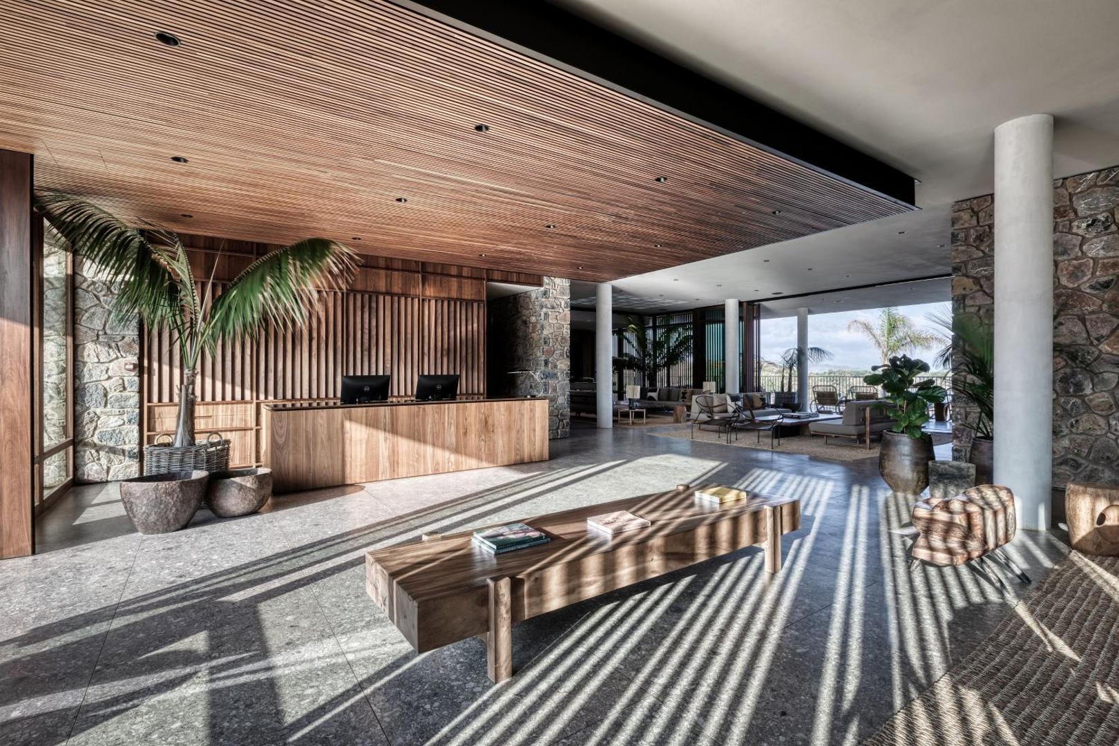 Domes Zeen Chania viesnīcas recepcijas zona ar modernu koka apdari, akmens sienām un plašu lobby telpu Krētā