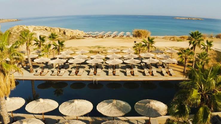 Domes Zeen Chania galvenais baseins ar salmu saulessargiem un skatu uz Egejas jūru un smilšu pludmali Hanijā