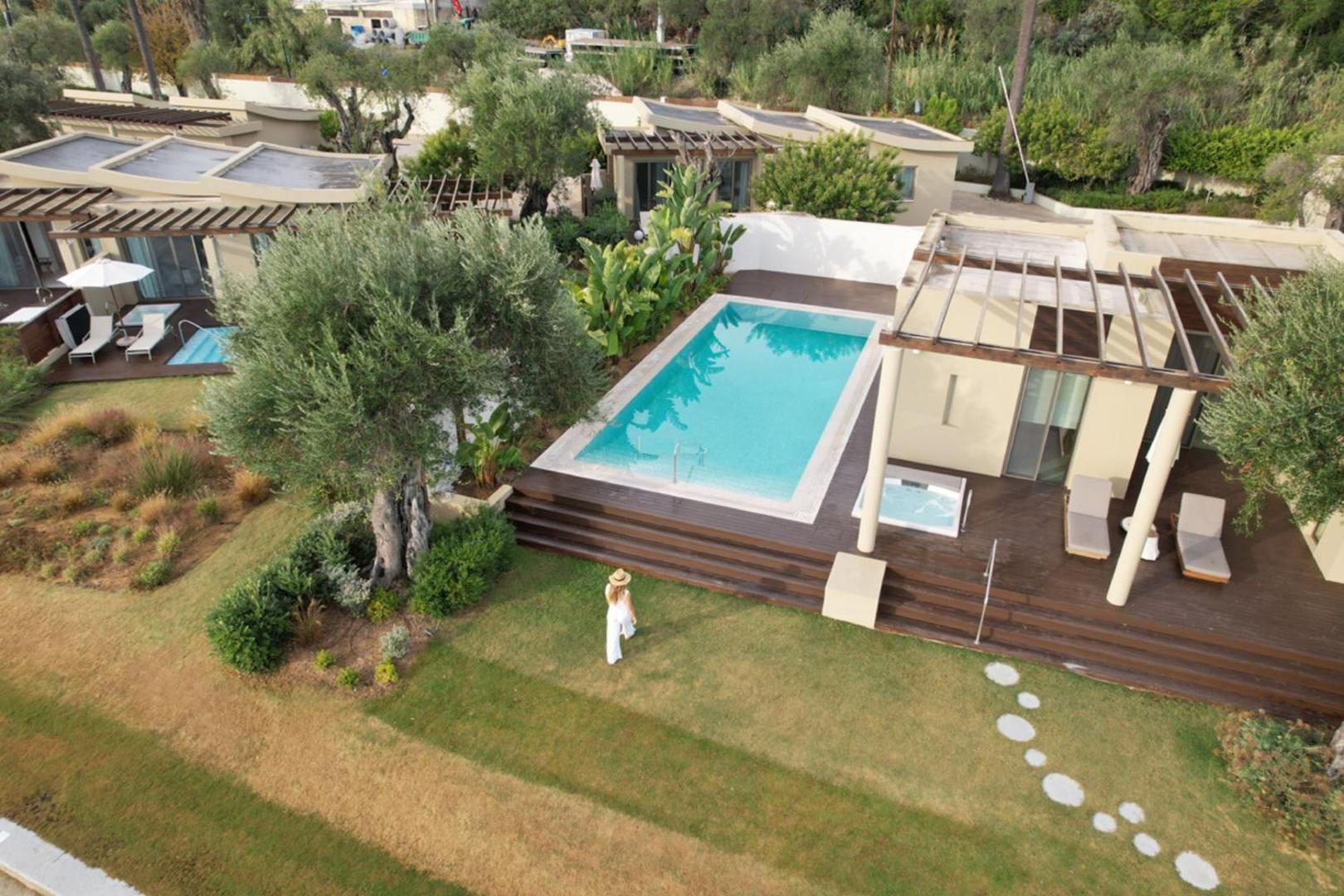 Domes Miramare Resort teritorijas skats no augšas ar olīvkokiem, privātiem baseiniem un bungalo tipa numuriem Korfu