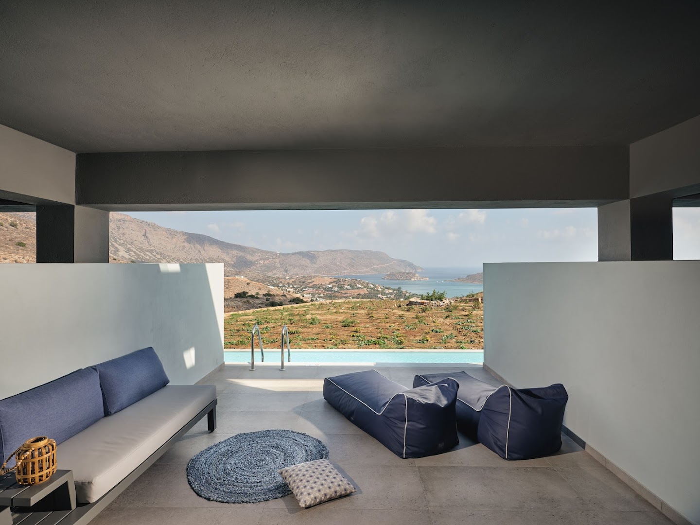 Domes Aulus Elounda Resort numura terase ar atpūtas krēsliem un tiešu piekļuvi baseinam, skats uz kalniem un jūru