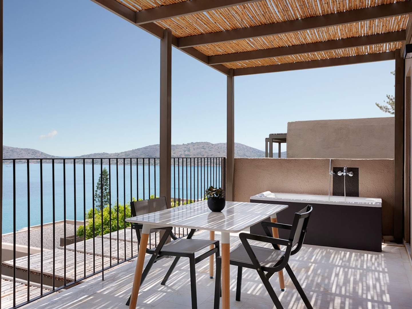 Domes Aulus Elounda Resort numura balkons ar pusdienu galdu un āra vannu, skats uz Spinalongas salu un jūru