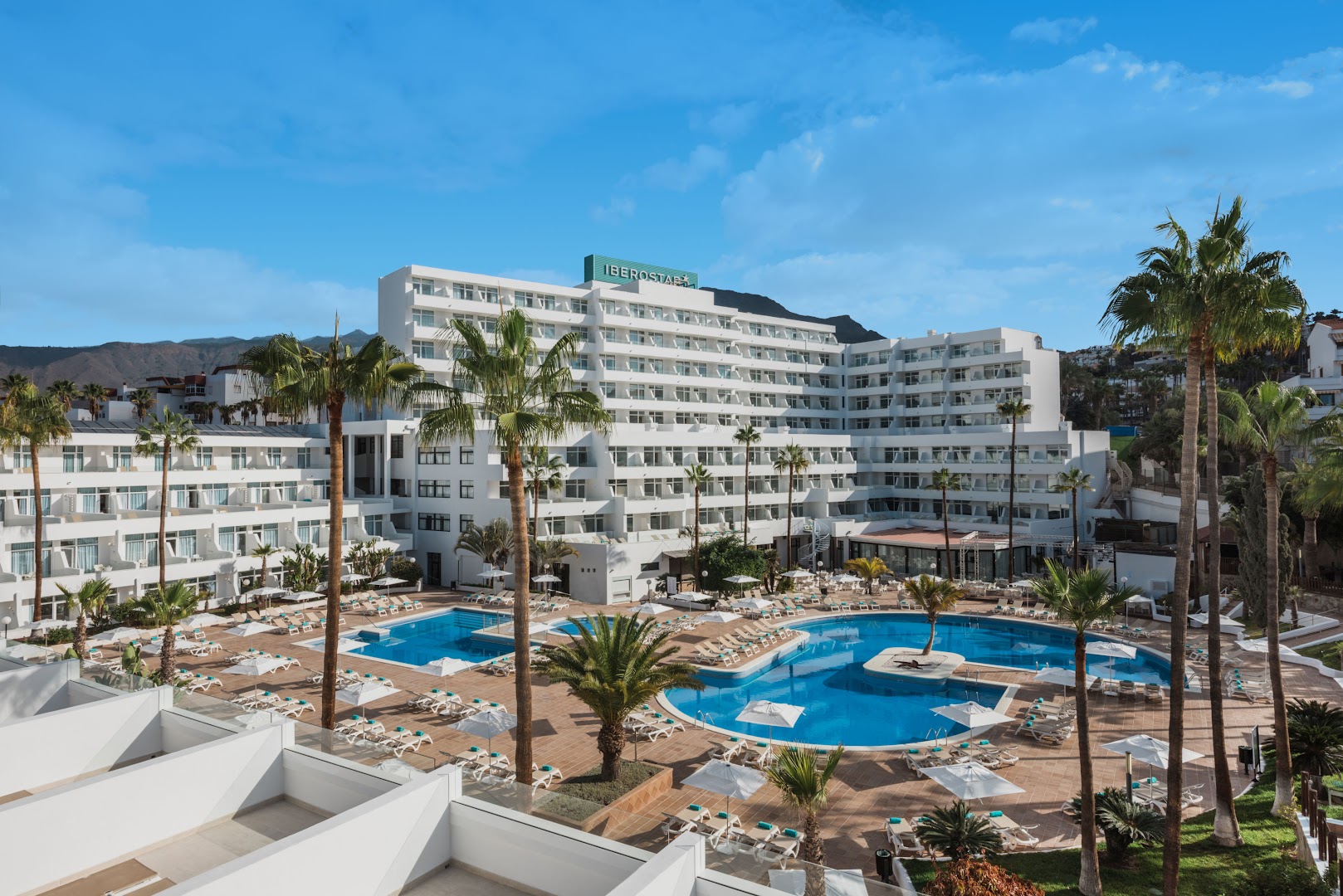 Iberostar Waves Las Dalias viesnīcas fasāde un iekšpagalms ar baseiniem Tenerifē — kalnu fons un labiekārtota atpūtas teritorija