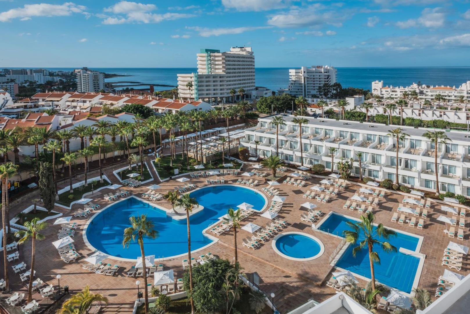 Iberostar Waves Las Dalias viesnīcas kopskats no augšas Tenerifē — plaša baseinu zona ar atpūtas krēsliem, palmām un skatu uz okeānu