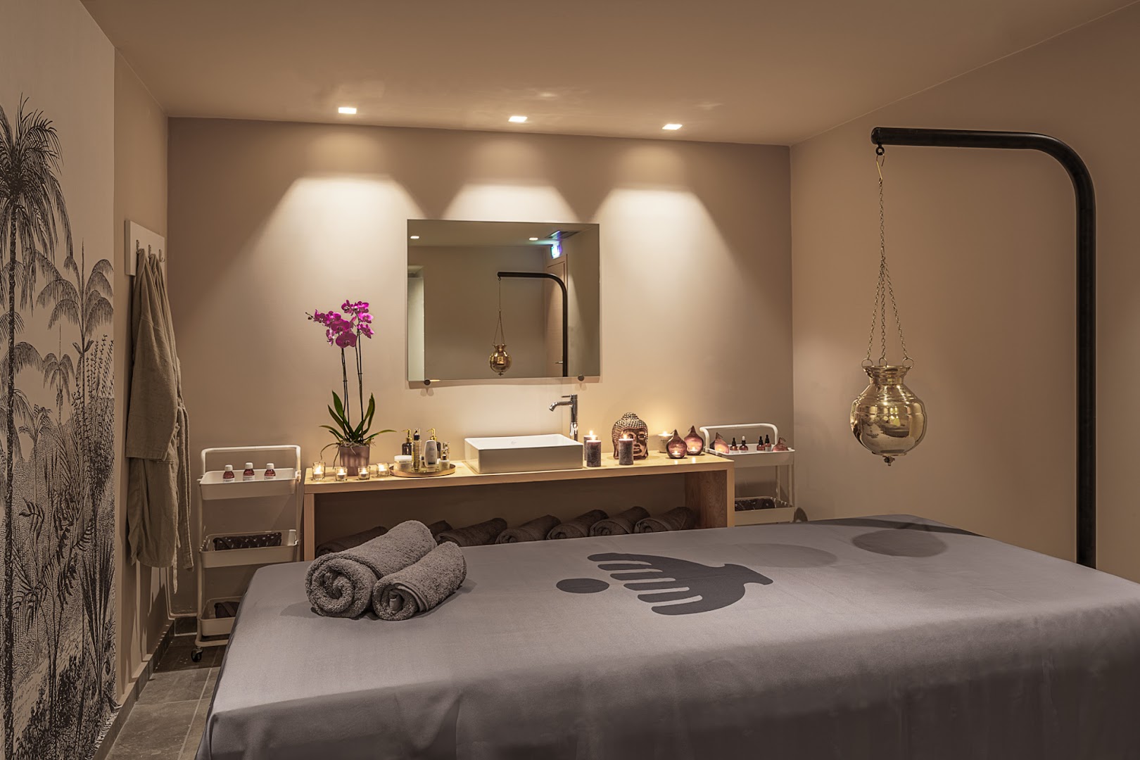 Cook's Club Corfu spa procedūru telpa ar masāžas galdu, siltu apgaismojumu, svecēm un tradicionāliem ajūrvēdas elementiem