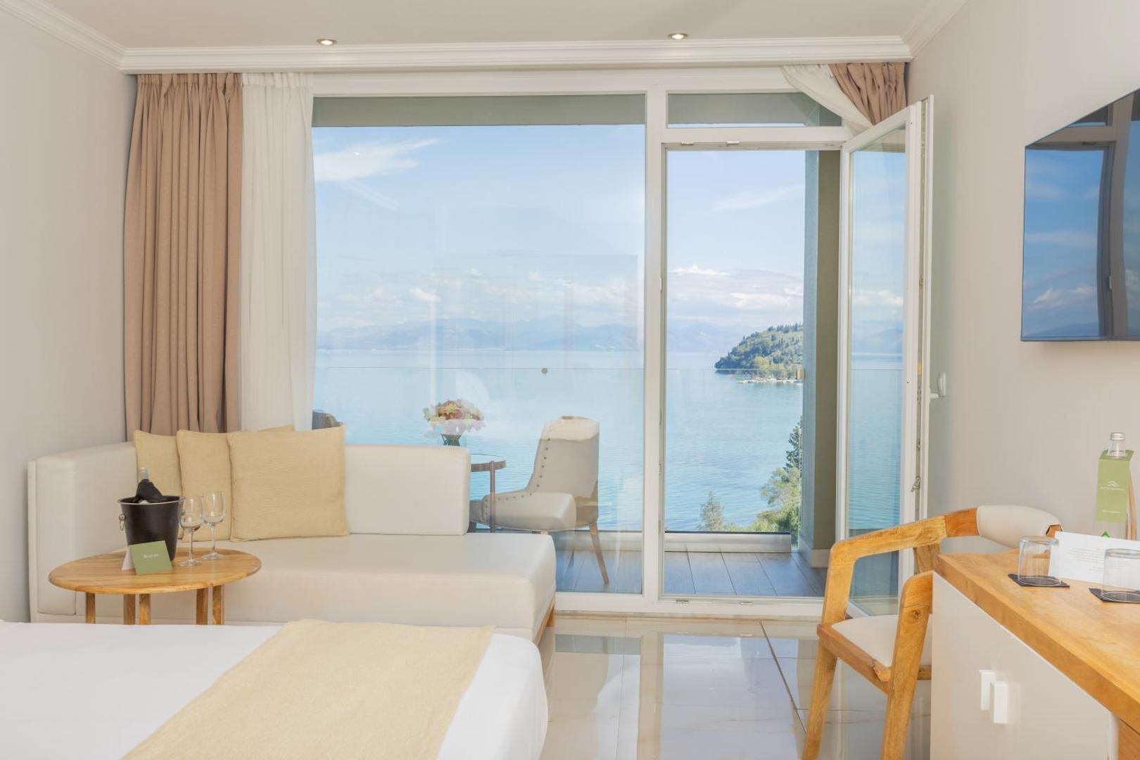 Skats no Mythos Palace Resort numura uz Jonijas jūru caur lieliem panorāmas logiem un balkonu