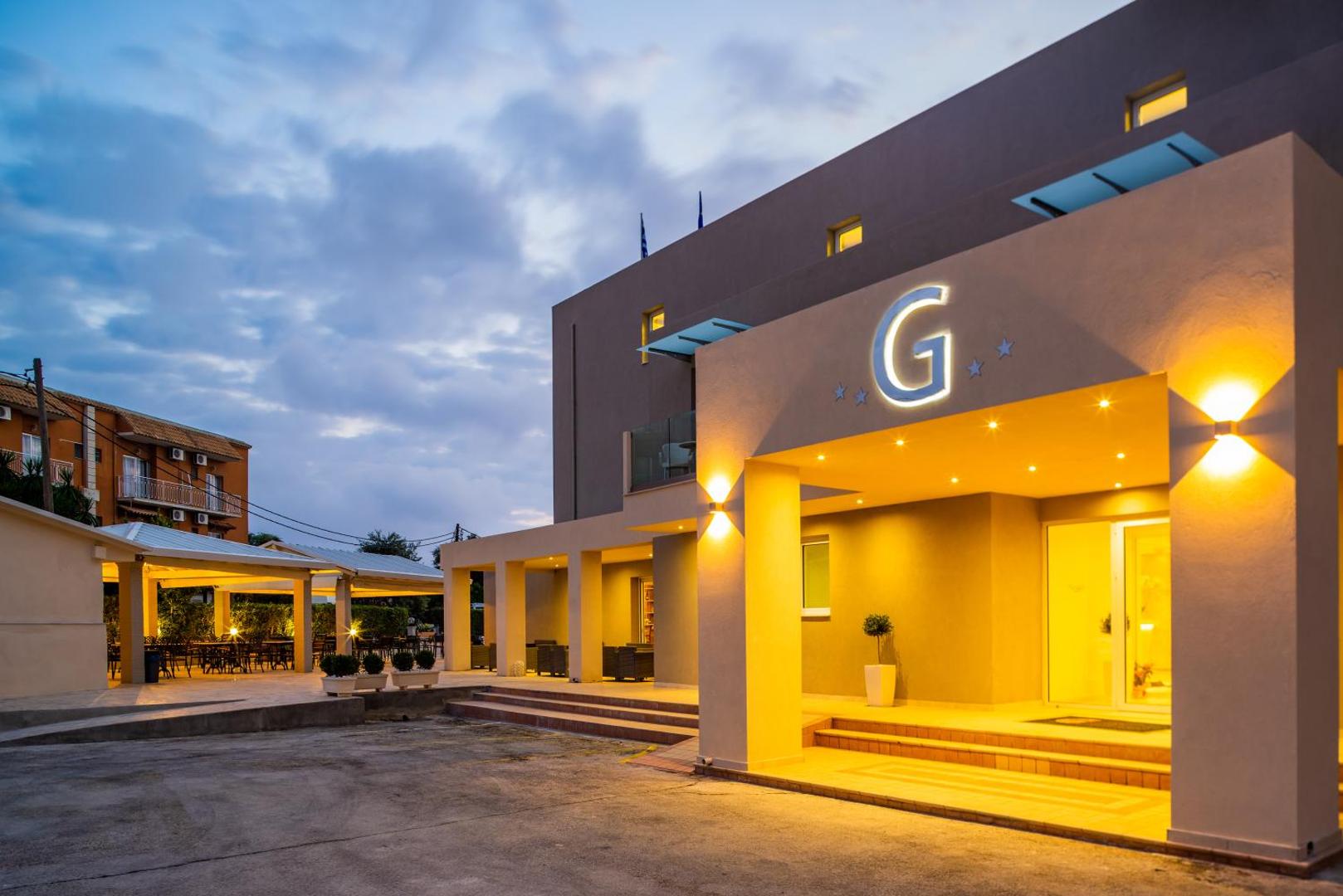 CNic Gemini Hotel ieeja vakarā ar siltu apgaismojumu un āra terasi Mesongi kūrortā Korfu salā Grieķijā