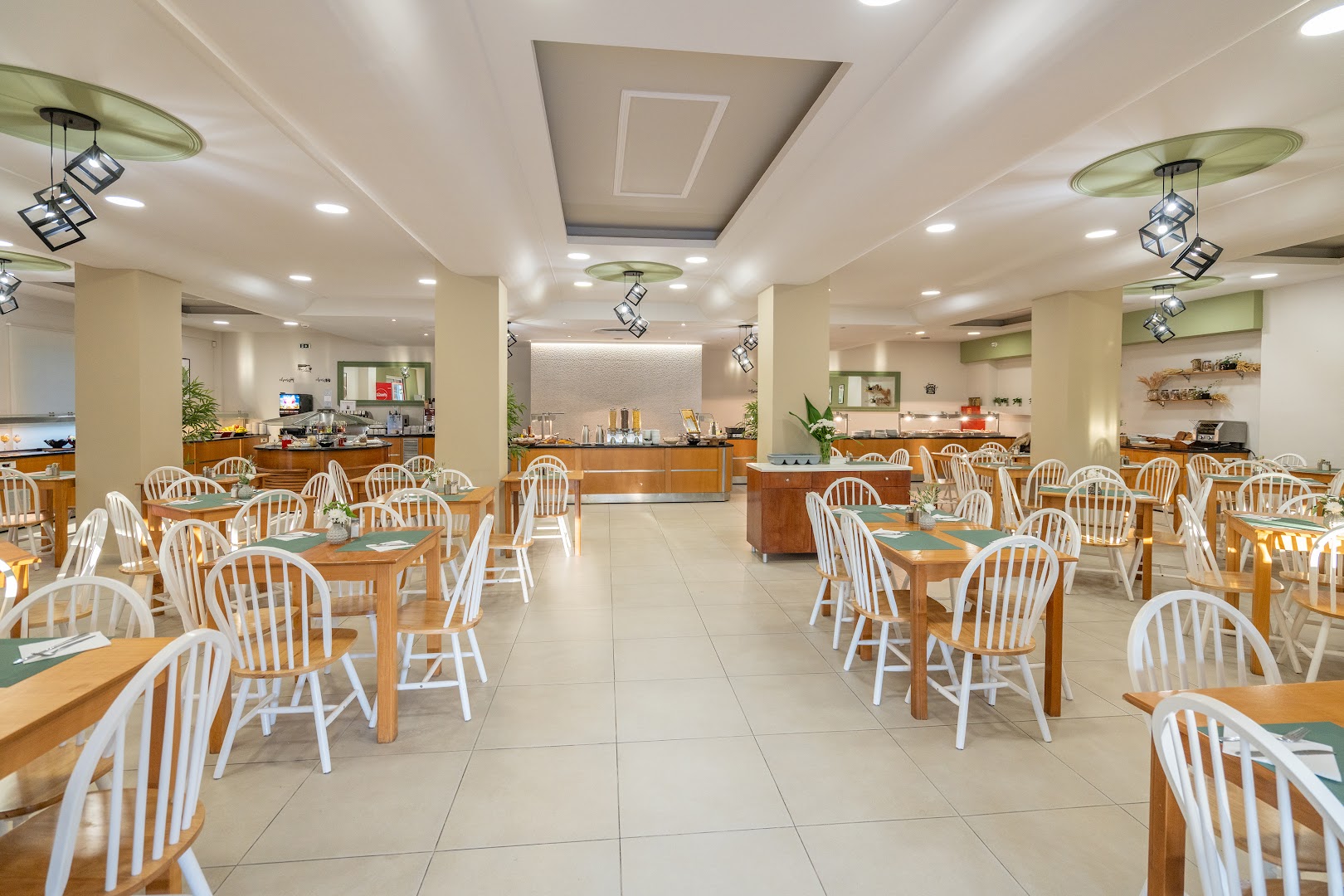 CNic Gemini Hotel galvenā restorāna zāle ar gaišām mēbelēm, koka galdiem un modernu apgaismojumu Korfu salā Grieķijā