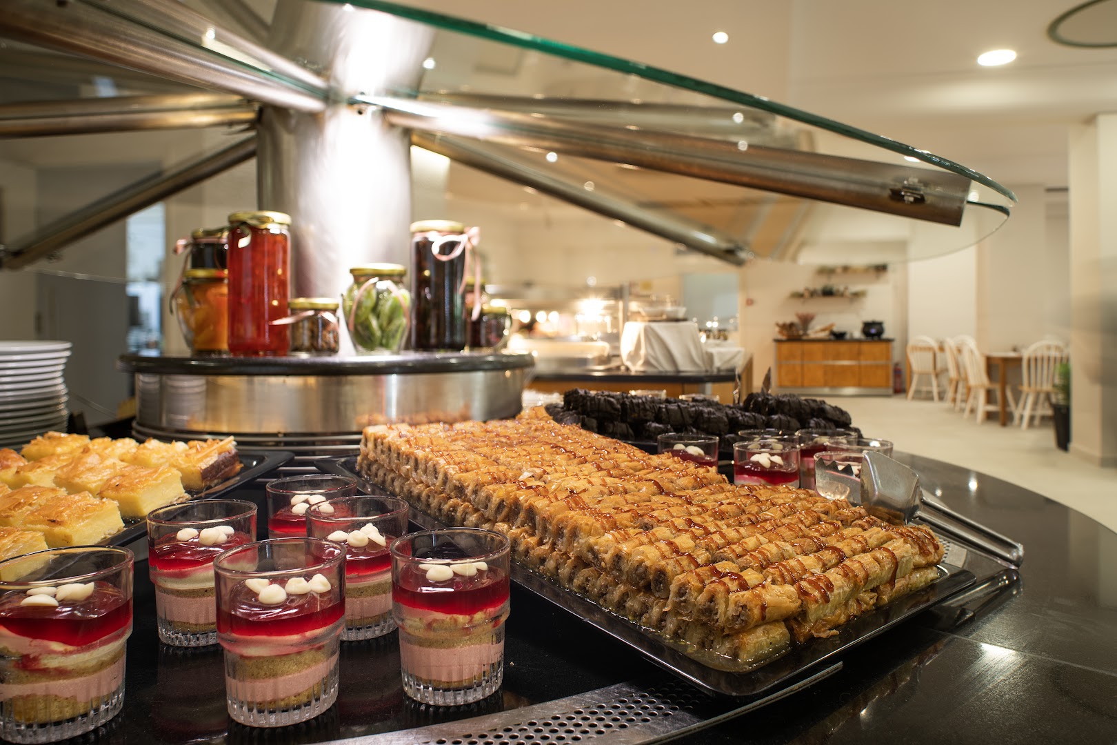 CNic Gemini Hotel desertu bufete ar baklavu, kūciņām un augļu ievārījumiem stikla traukos restorānā Korfu