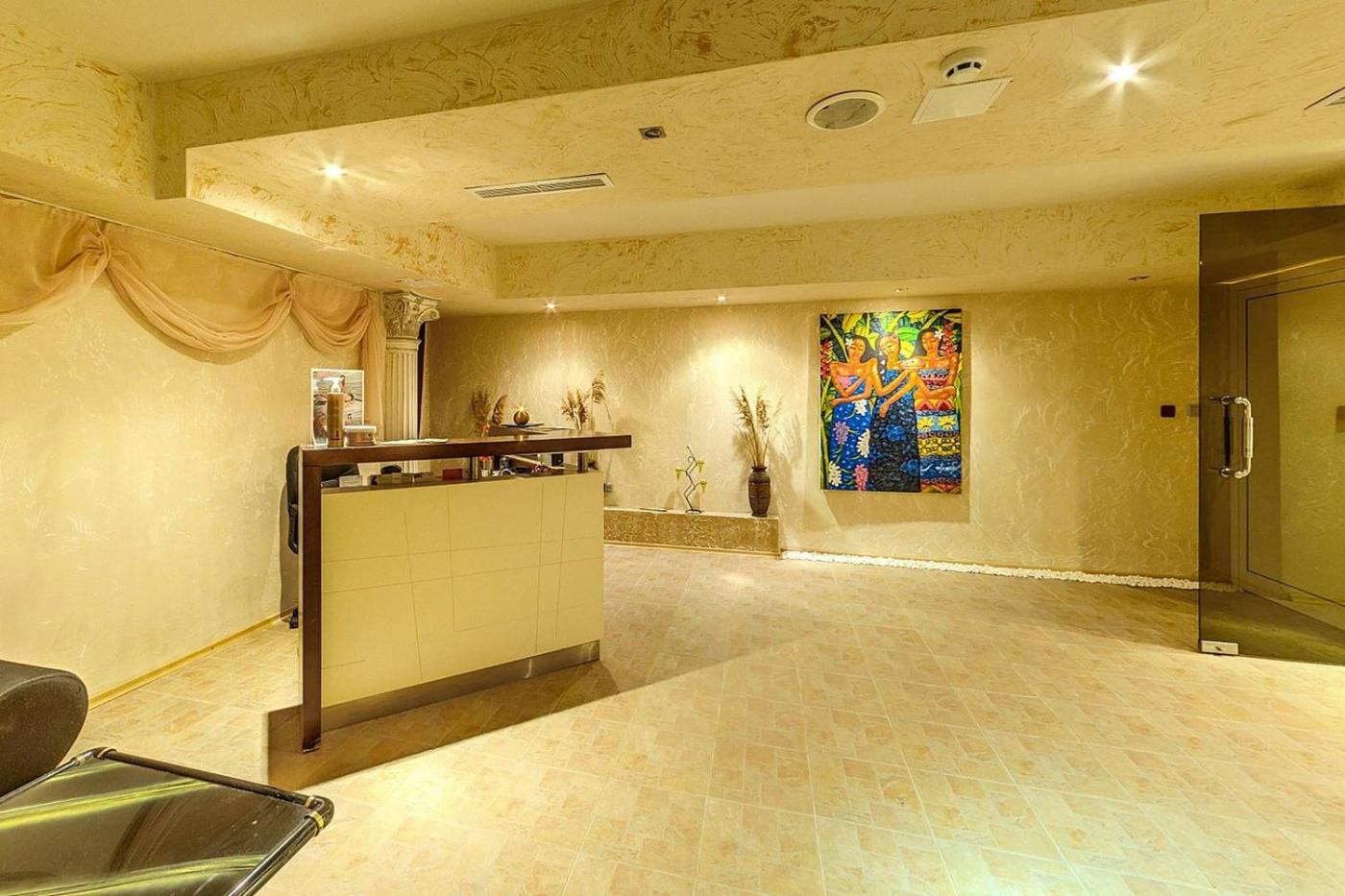 Festa Pomorie Resort spa centra recepcijas zona ar siltu apgaismojumu, dekoratīvu sienas gleznojumu un akmens apdari Bulgārijā