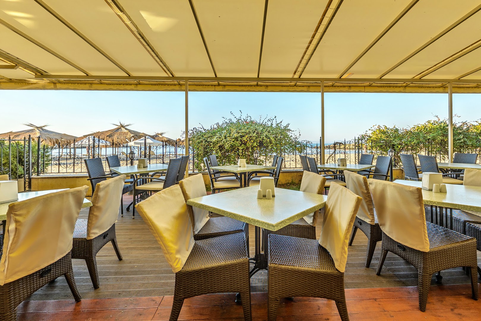Festa Pomorie Resort restorāna āra terase ar galdiņiem un krēsliem zem nojumes, skats uz pludmali un Melno jūru Bulgārijā