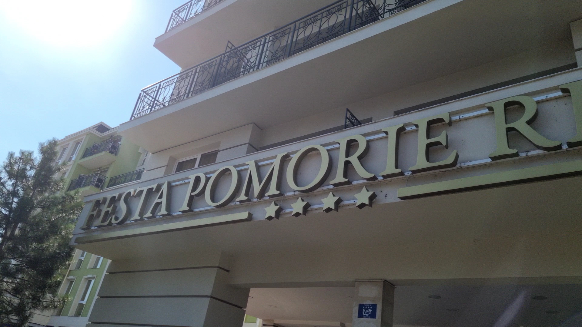 Festa Pomorie Resort 4* viesnīcas nosaukuma zīme pie ieejas, redzama moderna arhitektūra un balkoni