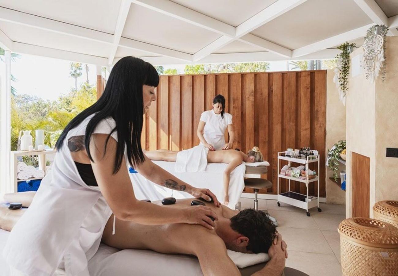 Profesionāla masāža ar karstajiem akmeņiem MYND Adeje spa zonā, kur divi terapeiti vienlaicīgi apkalpo viesus gaišā telpā