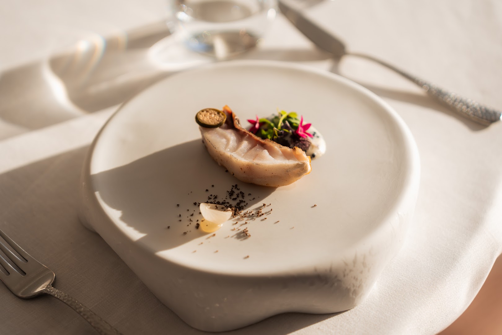 GF Victoria à la carte restorāna izsmalcināts zivs ēdiens ar dekoratīviem zaļumiem uz dizaina šķīvja — augstākās klases gastronomija.