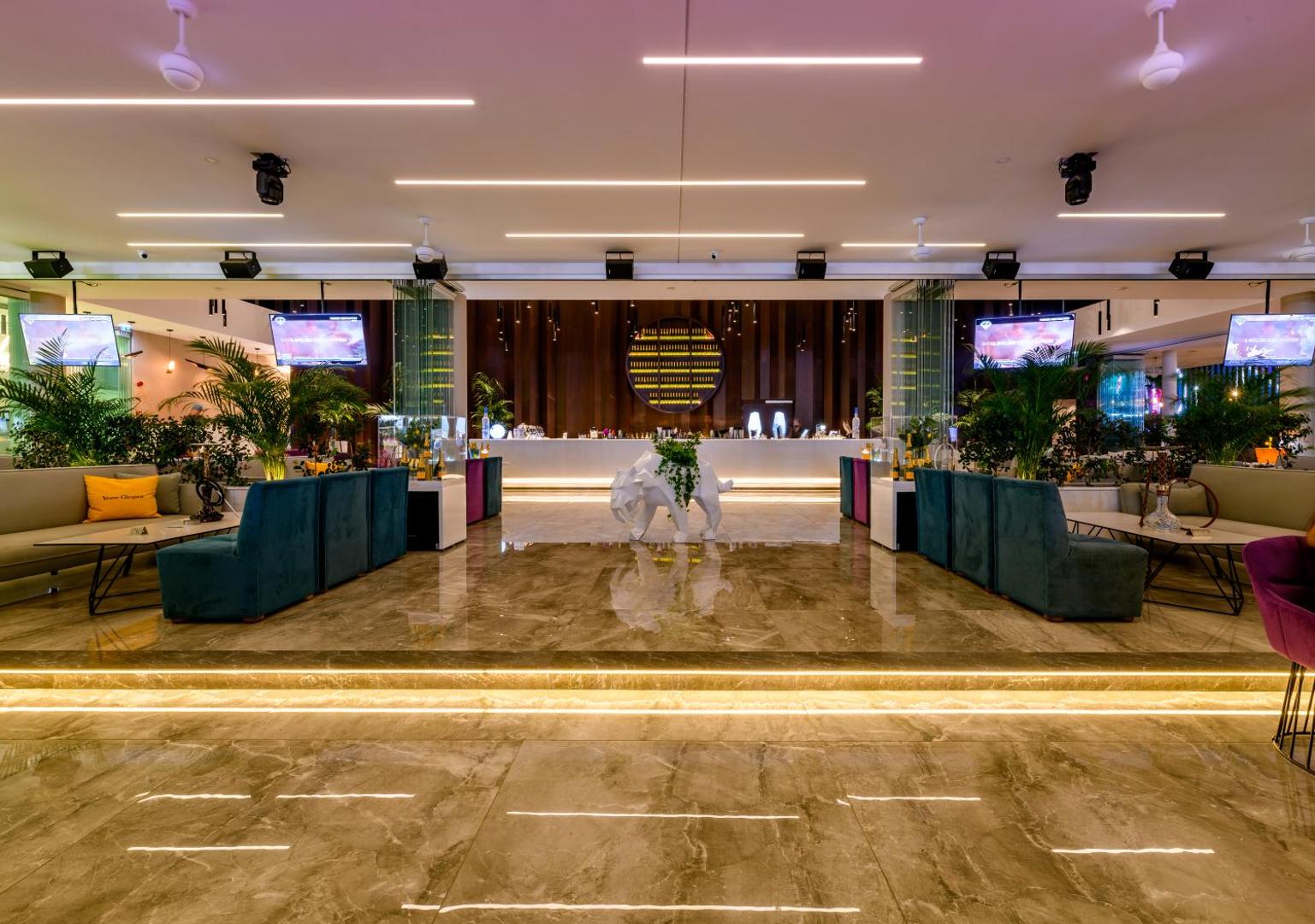 Tasia Maris Seasons Hotel vakara bārs ar modernu apgaismojumu, mīkstajiem dīvāniem, televizoriem un stilīgu leti centrā