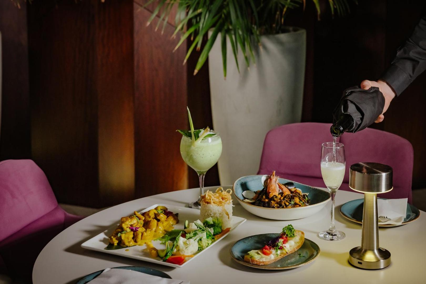 Tasia Maris Seasons Hotel restorāna vakariņas Aijanapā — eleganti pasniegti jūras velšu un vistas gaļas ēdieni ar dzirkstošo vīnu un kokteili.