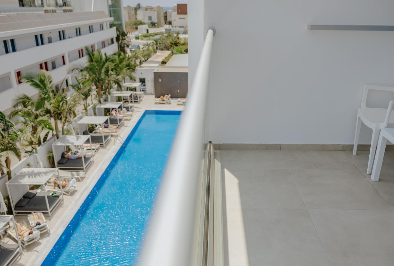 Skats no Tasia Maris Seasons Hotel numura balkona uz viesnīcas iekšpagalmu ar baseinu un modernām sauļošanās gultām