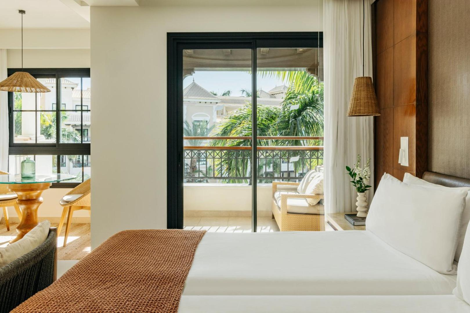 Gran Melia Palacio de Isora gaišs numurs ar balkonu Tenerifē — skats uz palmu dārzu, atpūtas zona un elegants interjers