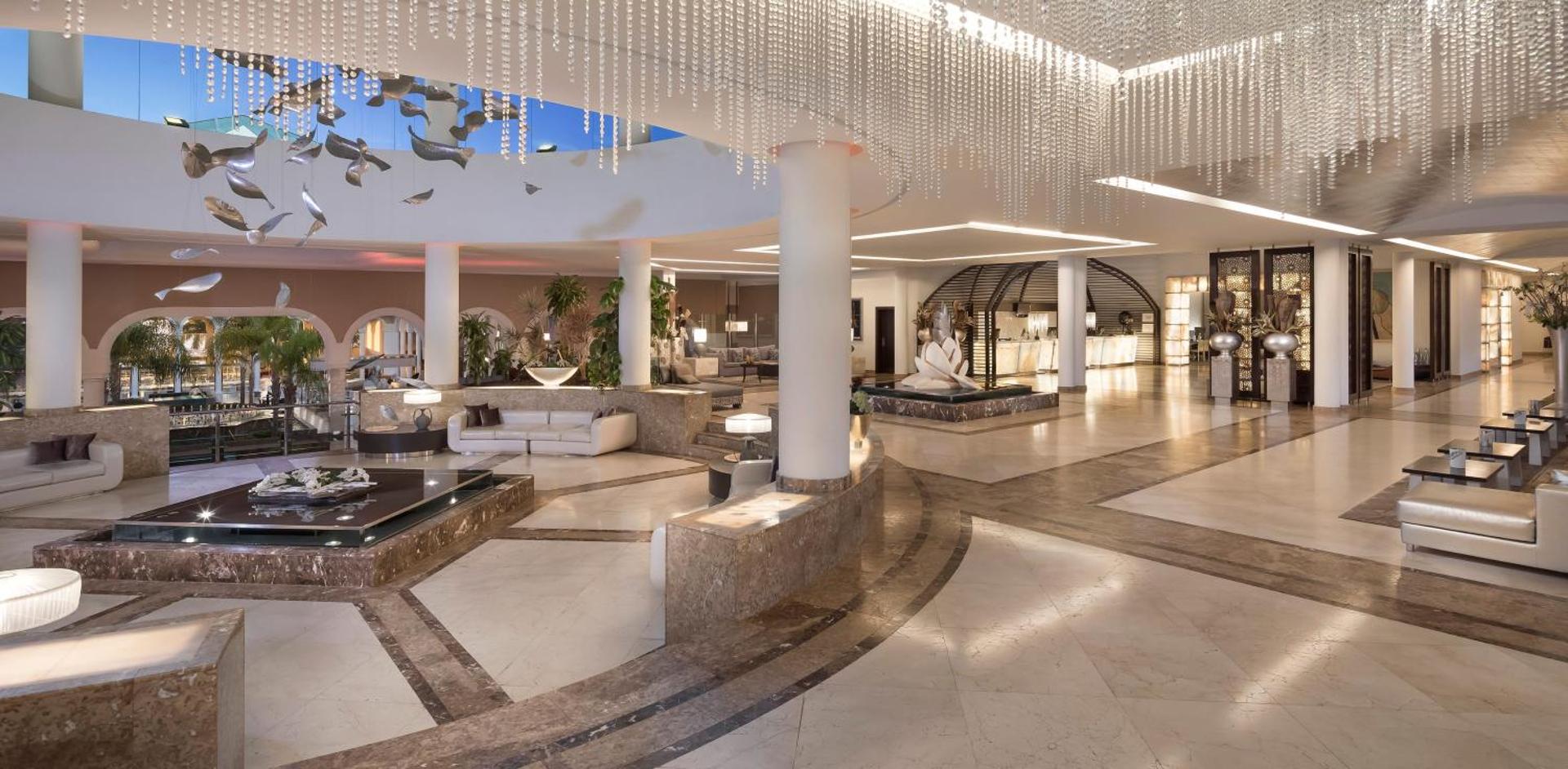 Gran Melia Palacio de Isora plašais un greznais vestibils ar marmora grīdām, kristāla lustrām un atpūtas zonām.