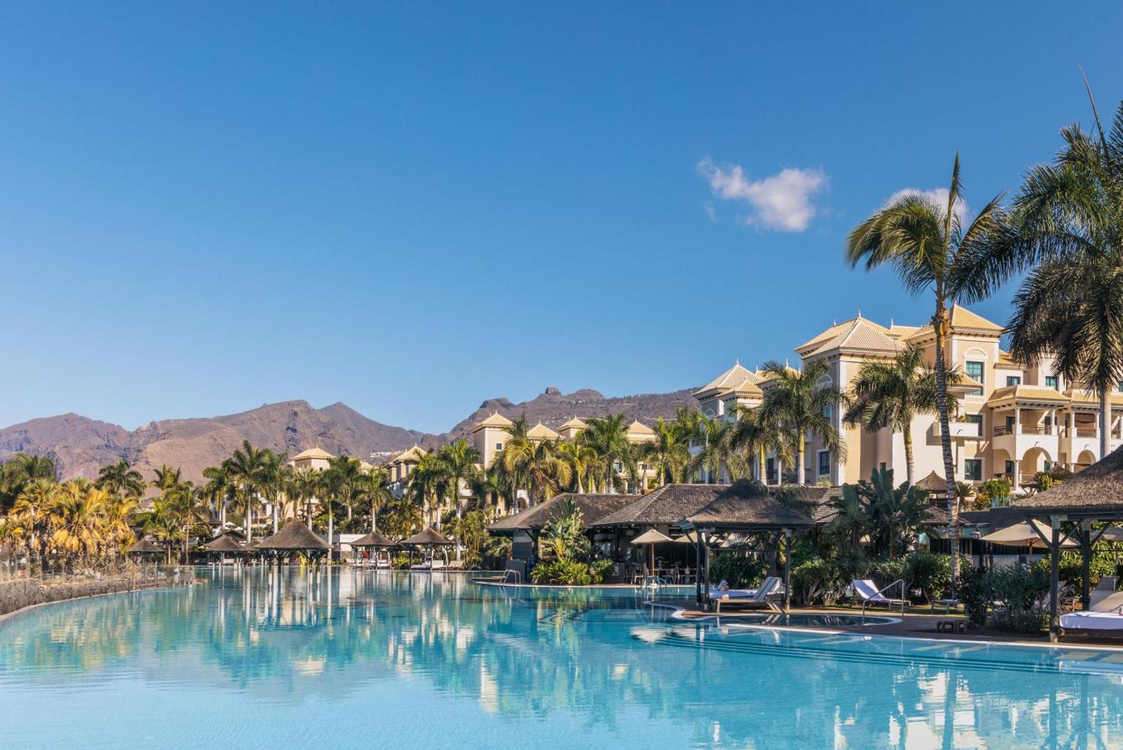 Gran Melia Palacio de Isora lielais baseins ar skatu uz kalniem un palmām — plaša atpūtas zona Tenerifes piekrastē