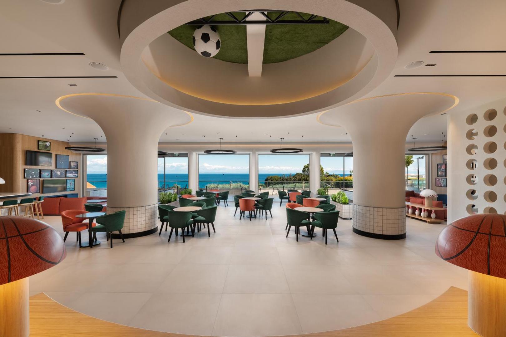Kresten Palace Hotel sporta bārs un atpūtas telpa ar futbola tematikas griestiem, basketbola bumbas lampām un skatu uz jūru