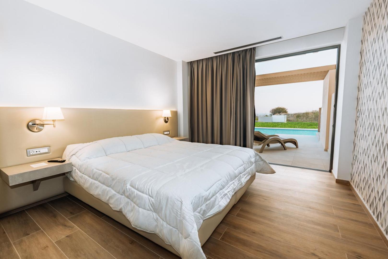 Kresten Palace Hotel moderns numurs ar lielu gultu un izeju uz terasi, kur atrodas baseins un sauļošanās krēsli