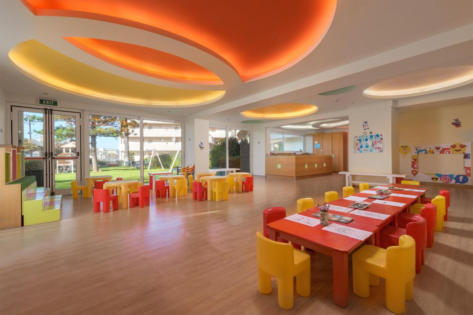Sun Beach Resort bērnu klubs ar krāsainiem galdiņiem un radošo zonu — plaša, gaiša telpa rotaļām un nodarbībām bērniem.