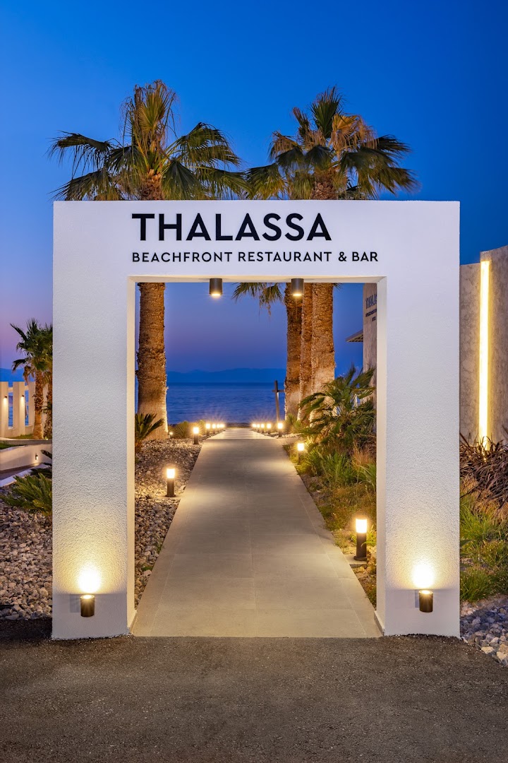 Sun Beach Resort restorāna Thalassa ieeja vakarā ar gaismas virtenēm, palmām un skatu uz jūru