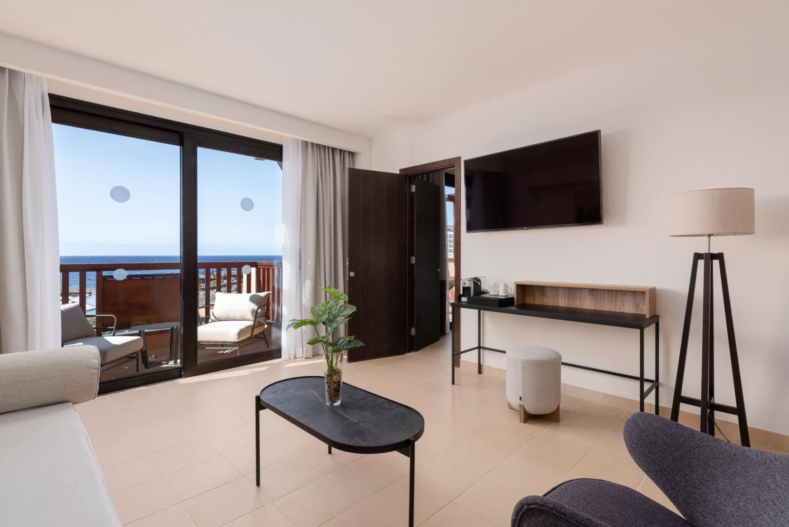 Barceló Tenerife Royal Level numura atpūtas zona ar dīvānu, kafijas galdiņu un izeju uz terasi ar skatu uz jūru