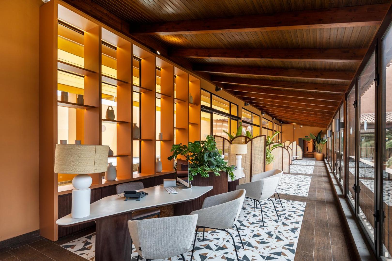 Barceló Tenerife Royal Level viesnīcas recepcijas zona ar stilīgiem krēsliem, koka griestu sijām un siltu apgaismojumu Tenerifes kūrortā