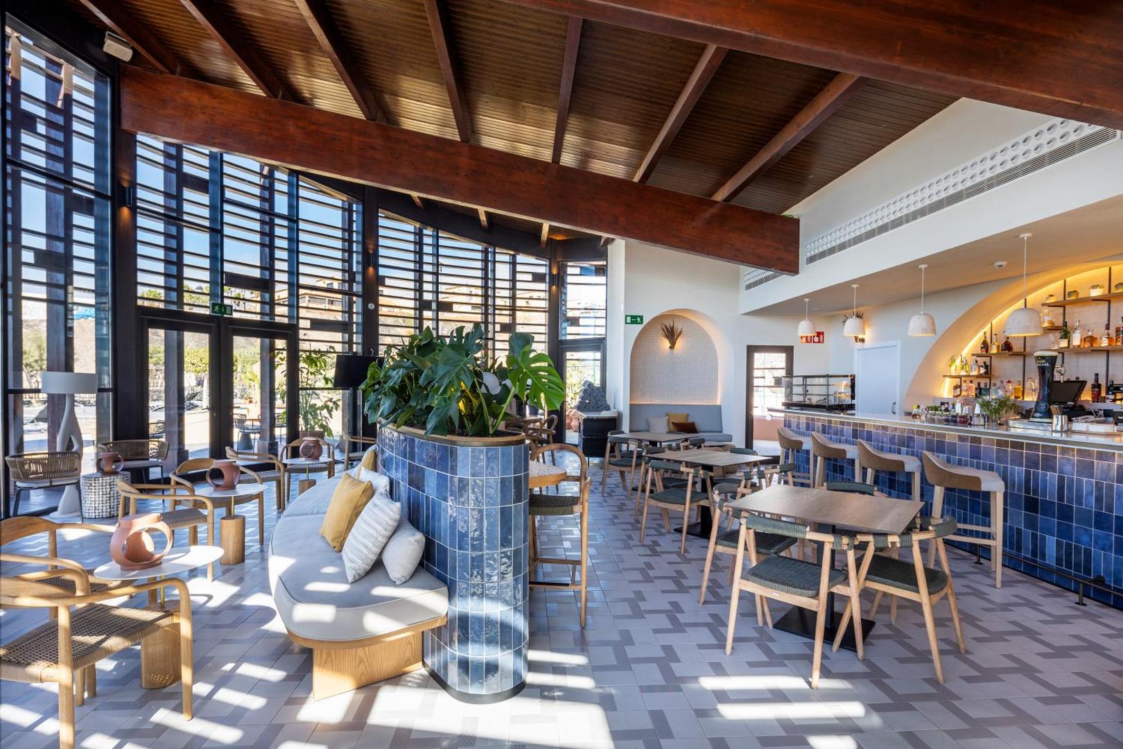 Barceló Tenerife Royal Level lobby bārs ar zilu flīžu apdari, koka mēbelēm un plašiem logiem Tenerifes dienvidu piekrastē