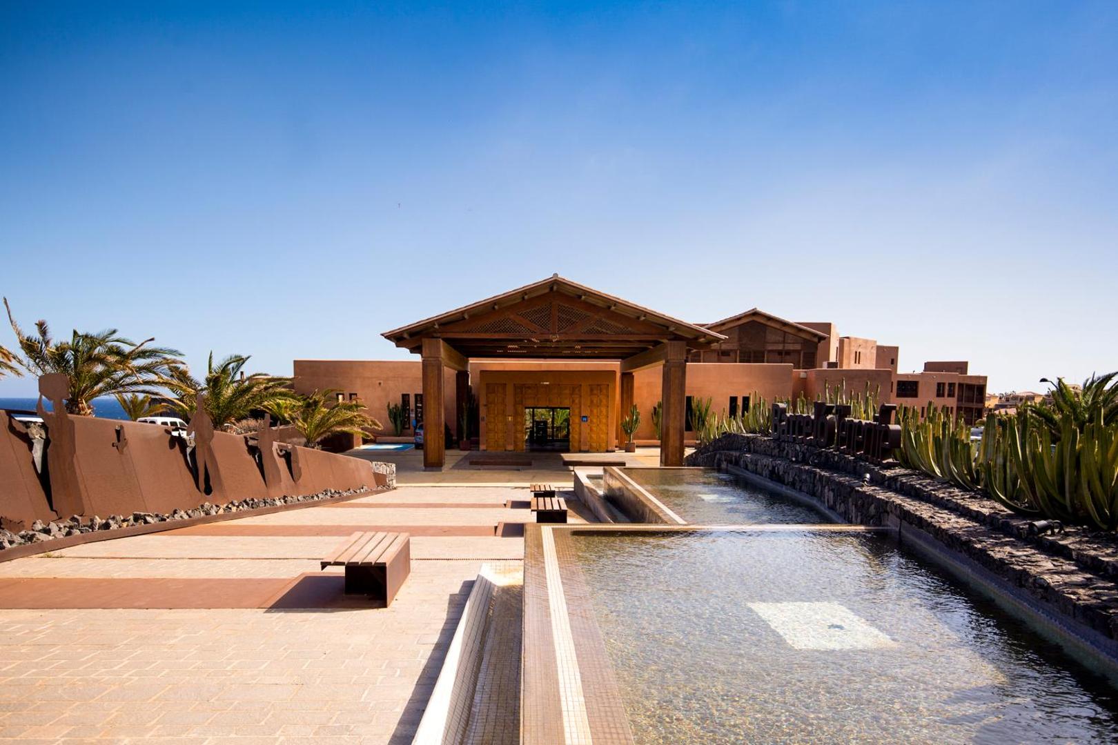 Barceló Tenerife Royal Level galvenā ieeja ar koka nojumi, dekoratīviem baseiniem un kaktusiem saulainā dienā Tenerifē