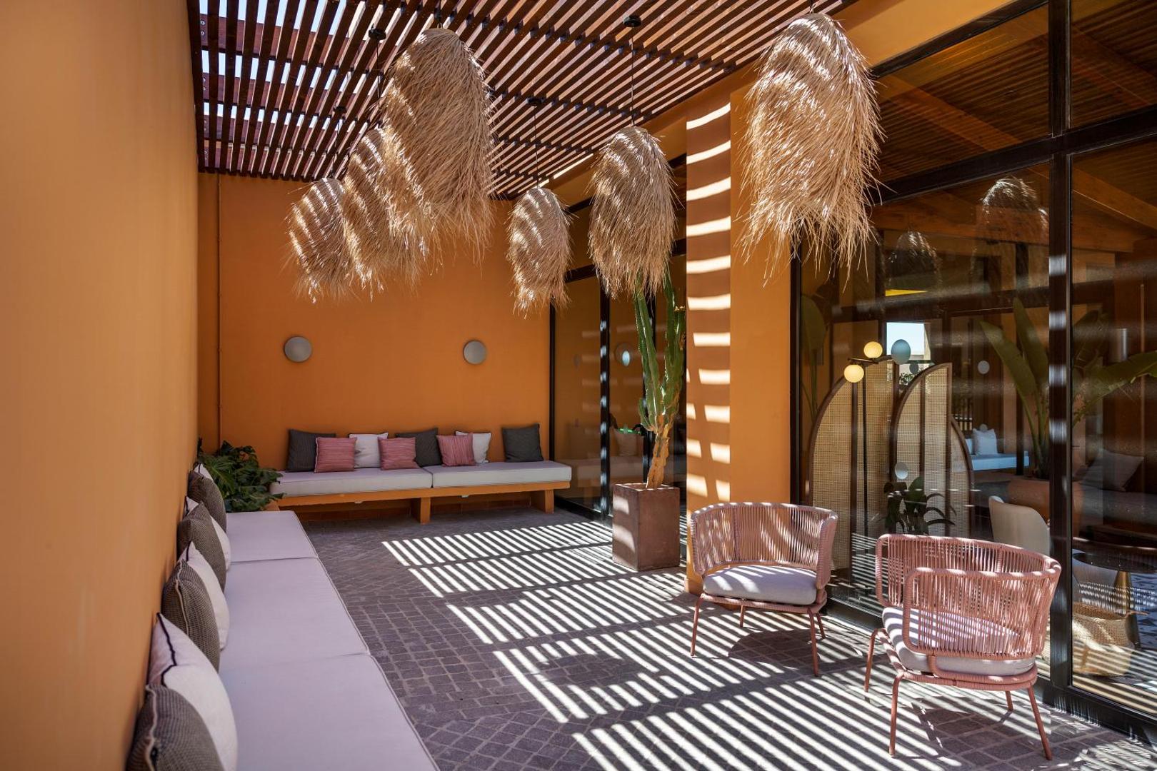 Barceló Tenerife Royal Level viesnīcas atpūtas zona ar pītiem krēsliem, dīvāniem un dekoratīviem elementiem siltos zemes toņos Tenerifē, Kanāriju salās