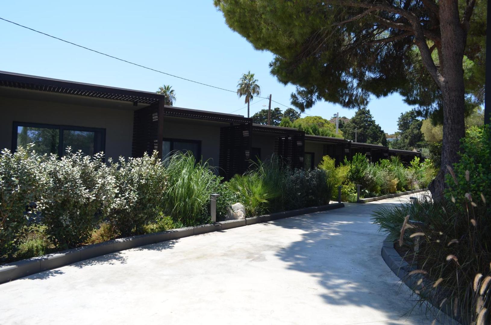 Gājēju celiņš gar Cook's Club Ialysos Rhodes vienstāva bungalo tipa numuriem ar privātām terasēm un koku pavēni.