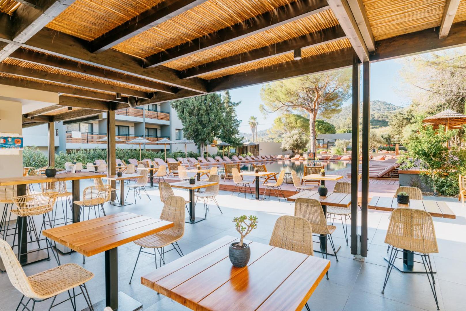Cook's Club Ialysos Rhodes āra terases restorāns ar koka galdiem un pītiem krēsliem pie baseina Rodas salā, Grieķijā