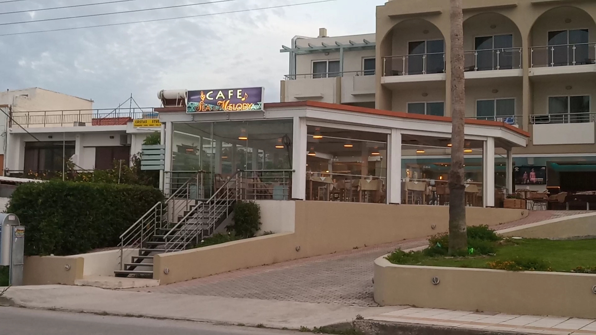 Sea Melody Beach Hotel Apartments kafejnīca un uzkodu bārs ar stiklotu terasi — atpūtas vieta viesiem pie ieejas