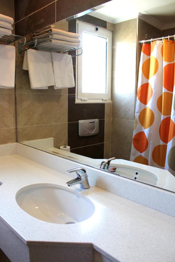 Sea Melody Beach Hotel Apartments numura vannas istaba ar gaišu izlietnes virsmu, lielu spoguli un krāsainu dušas aizkaru