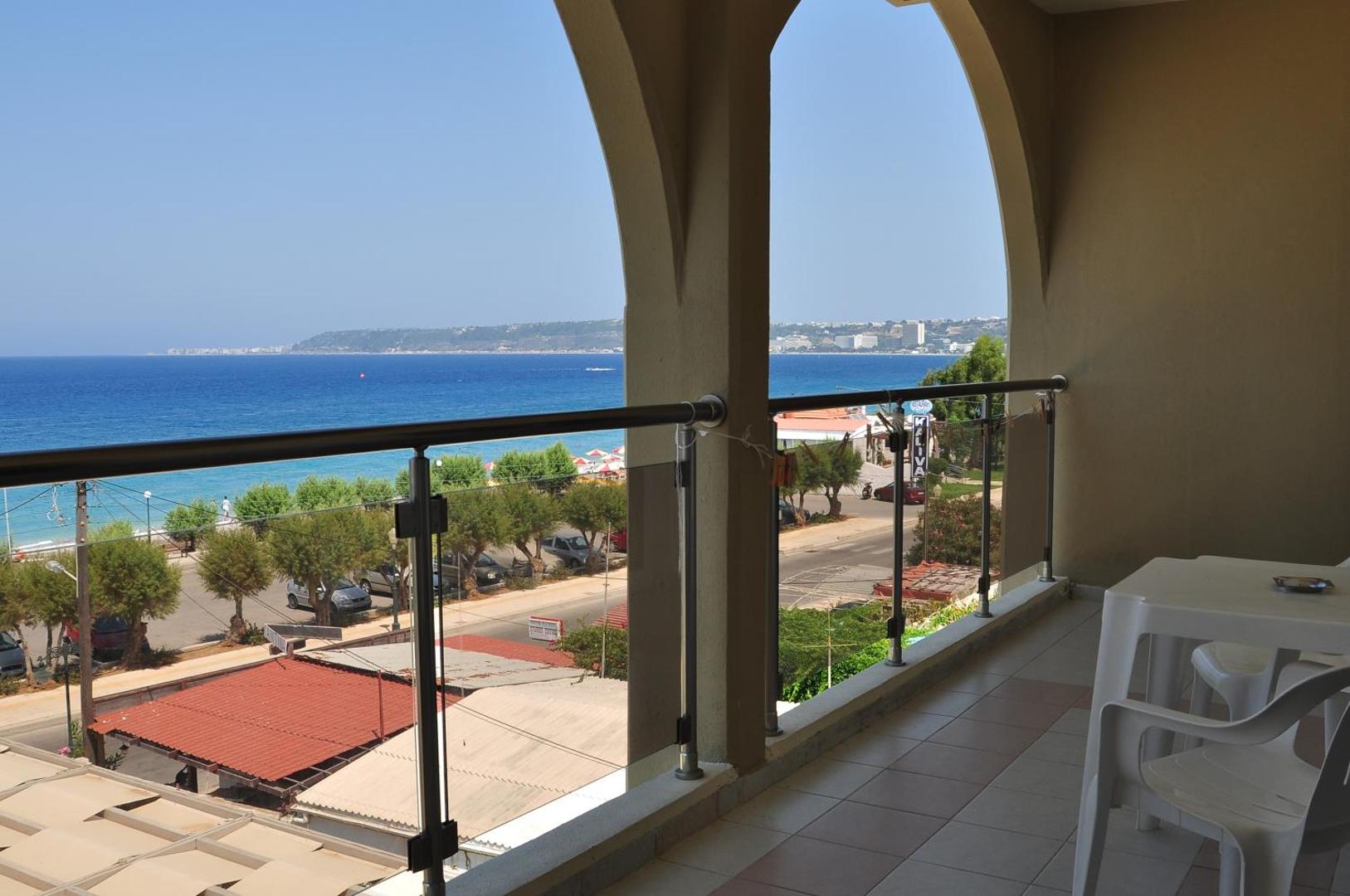 Skats no Sea Melody Beach Hotel Apartments balkona uz Vidusjūru Rodas salā — piekrastes ceļš, palmas un zilais jūras horizonts