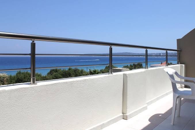 Sea Melody Beach Hotel Apartments terases skats uz jūru Rodas salā — minimālistisks dizains ar metāla margām un baltu krēslu