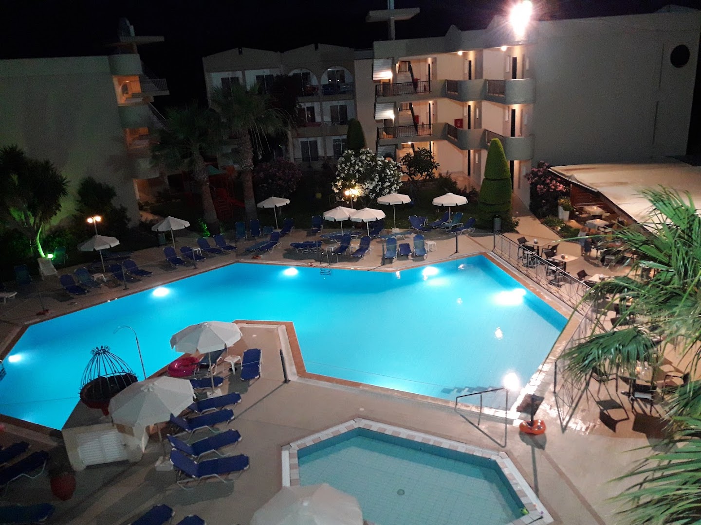 Sea Melody Beach Hotel Apartments nakts skats no augšas uz baseinu un bērnu baseinu Rodas salā — izgaismota viesnīcas teritorija