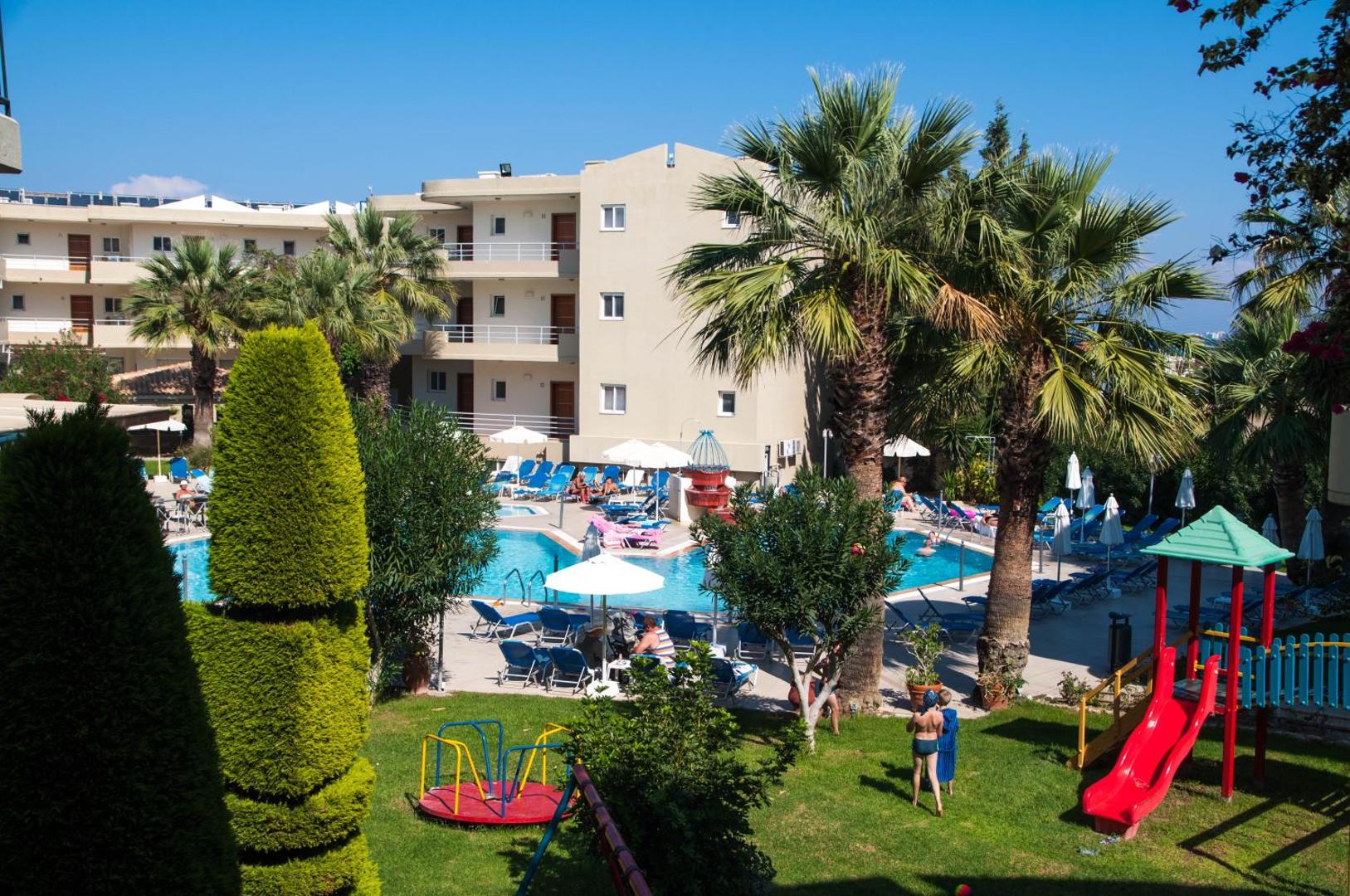 Sea Melody Beach Hotel Apartments skats no augšas uz baseinu, bērnu rotaļu laukumu un viesnīcas ēku Rodas piekrastē