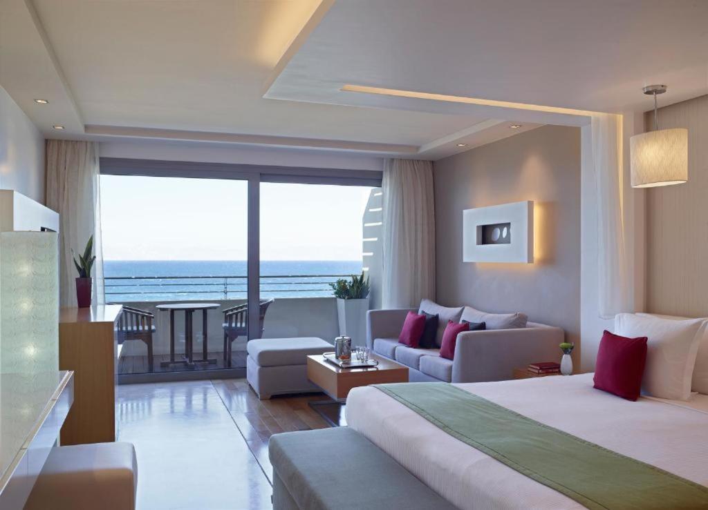 Amus Hotel & Spa gaišs numurs ar skatu uz jūru, balkonu, ērtu gultu un atpūtas zonu ar dīvānu