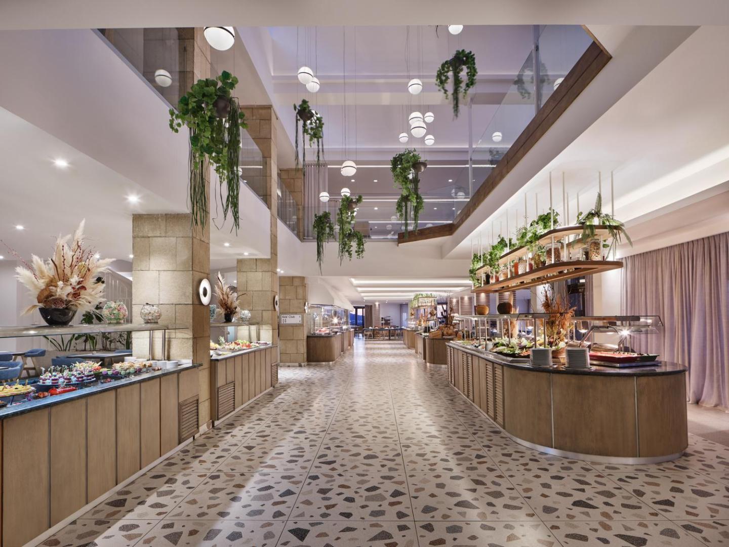 Amus Hotel & Spa modernais restorāns ar bagātīgu bufetes galdu, telpaugiem un gaišu, mūsdienīgu interjeru.