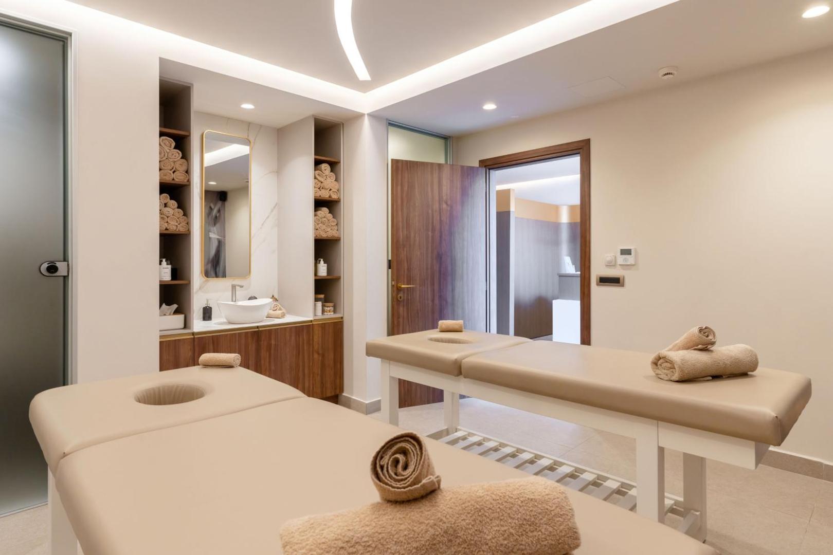 Bali Star Resort Hotel gaiša masāžas telpa ar divām gultām un modernu interjeru — spa procedūras viesiem Krētā