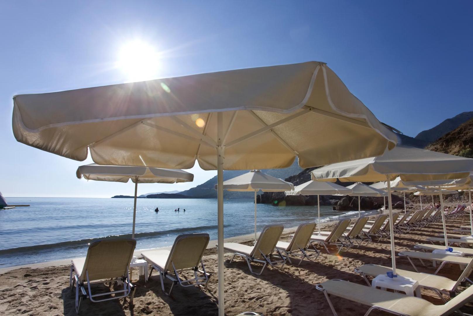 Bali Star Resort Hotel privātā pludmale ar saulessargiem un zviļņiem saulainā dienā — skats uz mierīgu jūru un kalniem