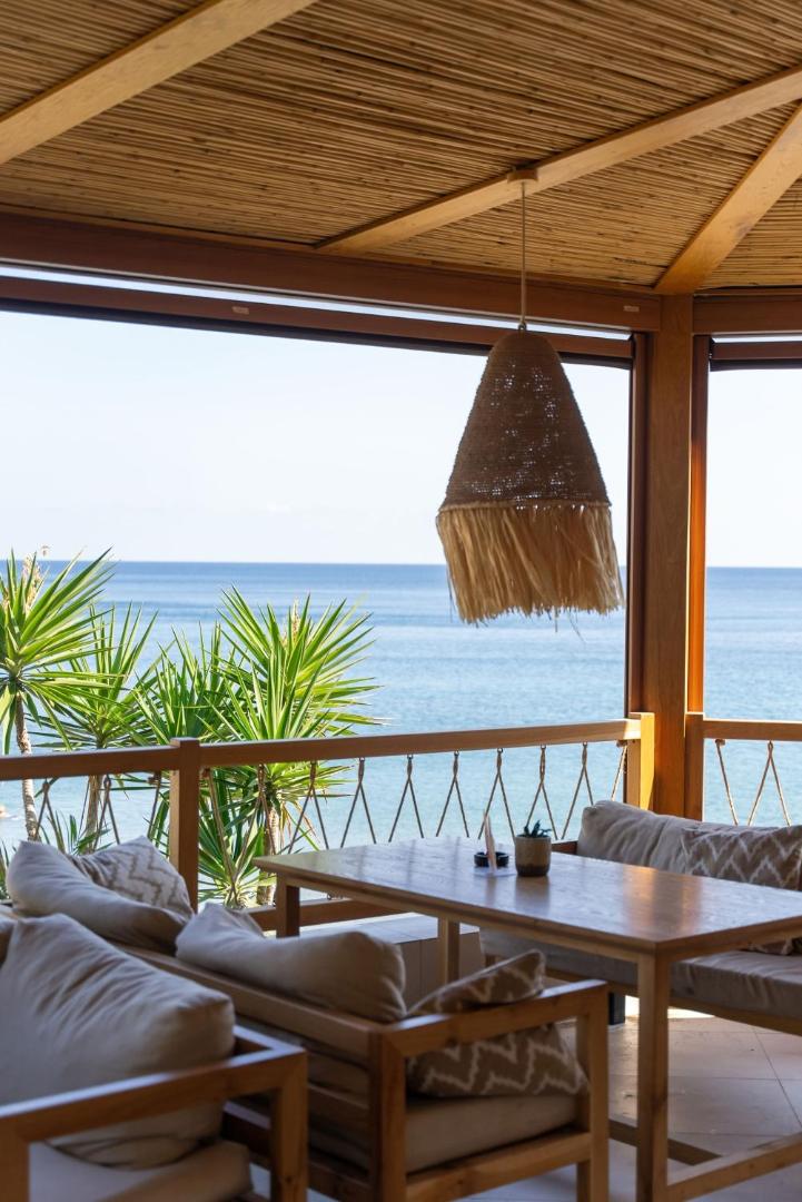 Bali Star Resort Hotel restorāna terase ar skatu uz jūru Bali ciemā, Krētā — koka mēbeles un pīts gaismeklis