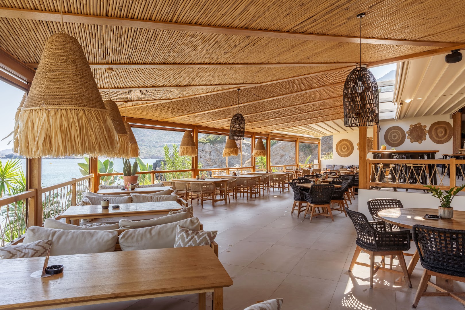 Bali Star Resort Hotel bāra un atpūtas zona ar mīkstiem dīvāniem, bambusa griestiem un skatu uz piekrastes klintīm