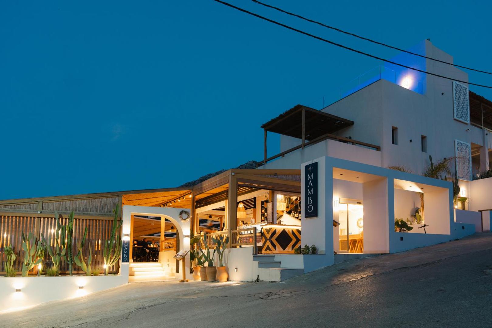 Bali Star Resort Hotel modernā fasāde un Mambo bārs vakara apgaismojumā Bali kūrortā, Krētā — arhitektūra un kaktusi
