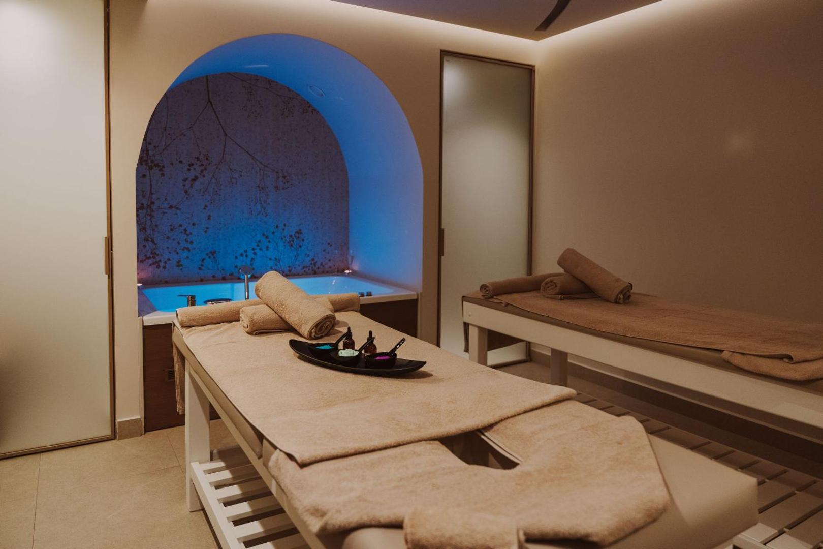Bali Star Resort Hotel spa procedūru telpa ar divām masāžas gultām un džakuzi vannu fonā — relaksējošs apgaismojums