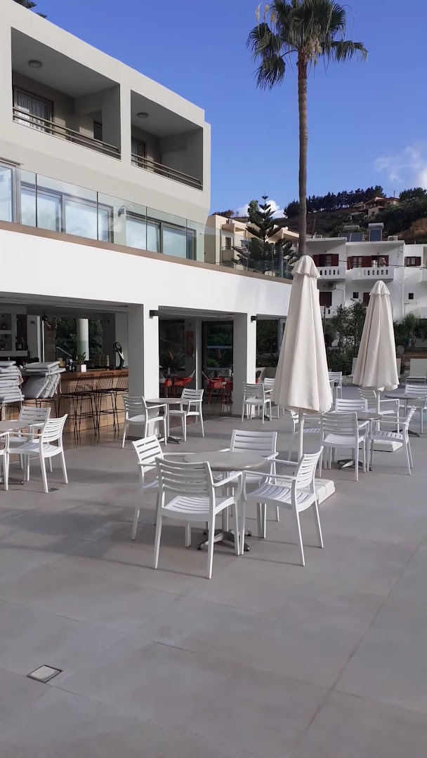 Bali Star Resort Hotel āra bārs un kafejnīca ar baltiem krēsliem un saulessargiem pie viesnīcas ēkas Bali ciemata piekrastē